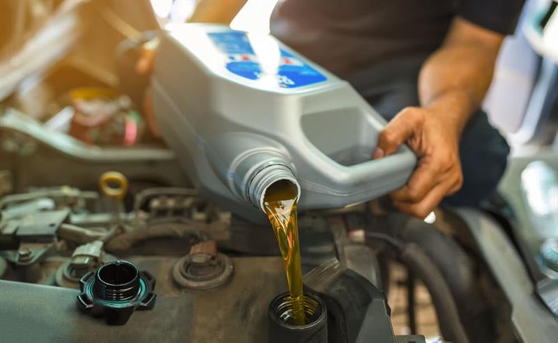 A technician pouring new motor oil into a Chevy Equinox